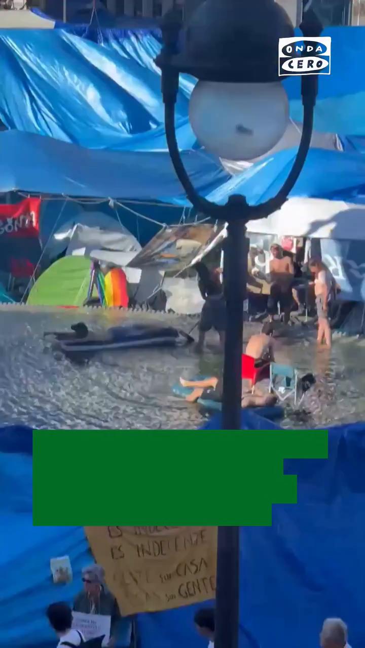 📹 Los acampados de Sol utilizan la fuente de la estatua de Carlos III como piscina para bañarse con colchonetas
