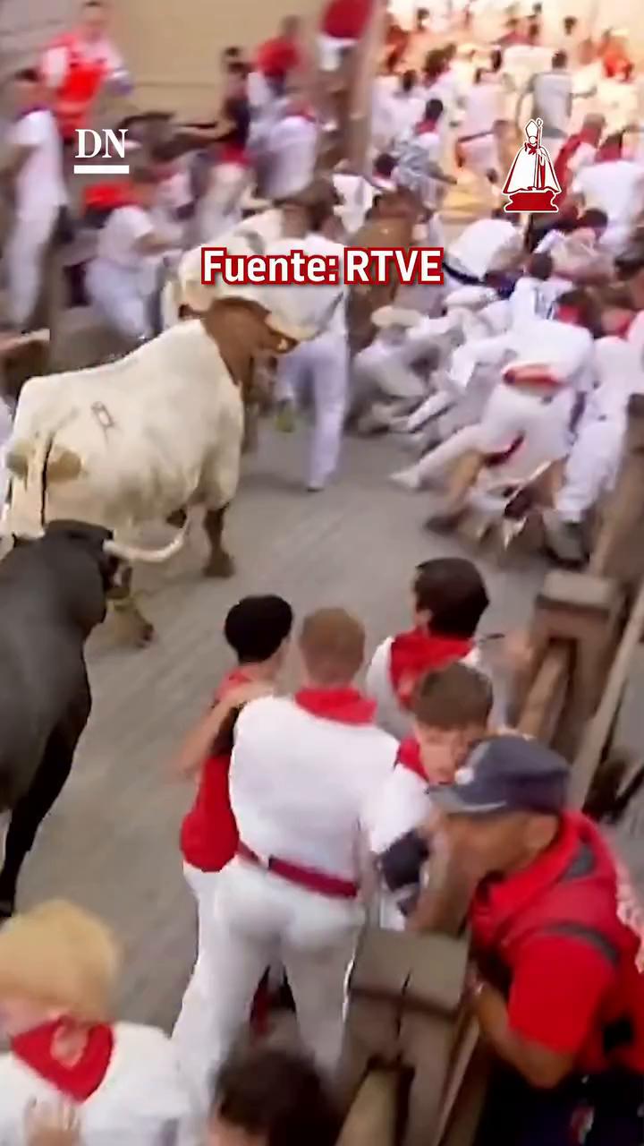 Un toro barre con su pala a varios corredores en mitad de la calle