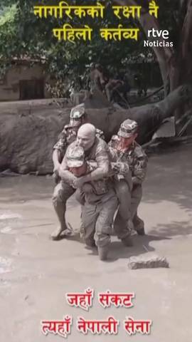 Tres soldados rescatan a un hombre completamente cubierto de barro.